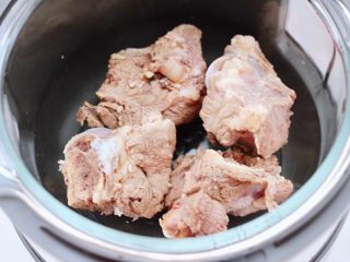 5、筒骨土豆胡萝卜汤,把焯好水的筒骨放入九 阳蒸汽电饭煲里。