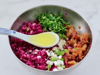 8、紫甘蓝鸡肉馅饼,把腌制好的紫甘蓝,葱姜和香菜末倒入腌制好的鸡肉里,加入花生油。