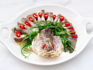 9、清蒸鲈鱼,把蒸鱼后的汤汁倒掉不用，先摆上小米辣，再撒上葱丝。
