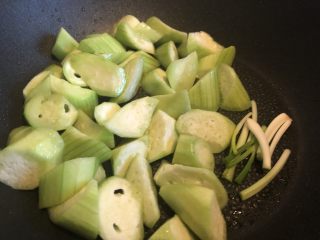 9、低脂晚餐之农家丝瓜煲,倒入丝瓜块与葱白,翻炒均匀。