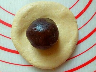 7、#甜味#香甜糯的南瓜饼#,取一块面团，用手掌心按扁，放上豆沙馅，再揉圆。(每个面团约50g，豆沙馅每个约20g)