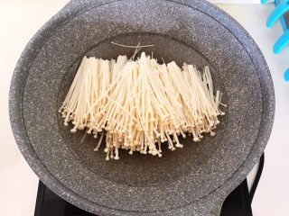 5、酸汤肥牛金针菇,锅里加入冷水烧开，加入金针菇，焯水1分钟