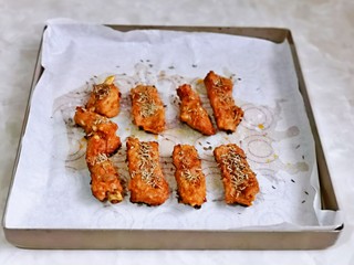 12、孜然排骨,20分钟后取出烤盘，撤掉锡纸，再铺上油纸，摆放上肋排，撒上孜然粒。