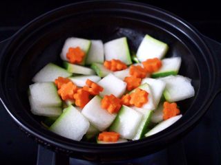 6、墨鱼丸子冬瓜木耳煲,放入冬瓜片，大火快速翻炒均匀，加入胡萝卜，继续大火翻炒片刻。