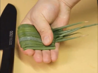 1、葱油鲈鱼,葱去葱白,留葱叶,对折卷起来,用手指控制住