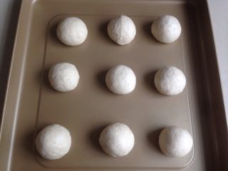7、黑豆红枣豆浆小餐包,发酵好的面团取出，用手掌压出面团里的气体，将面团分成9等份，滚圆，放在烤箱自带的不粘烤盘上
