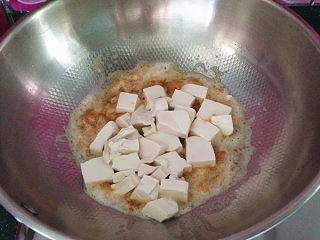 7、#了不起的小番茄# 蟹黄豆腐烩番茄,用锅铲捻碎炒融炒出油沙后下豆腐块