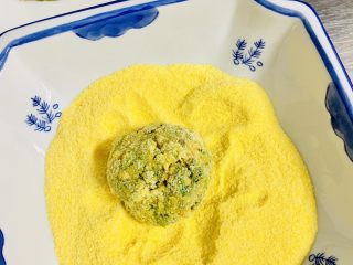 6、玉米面菜团子,取一个小菜球 让小菜球全部粘上玉米面粉。