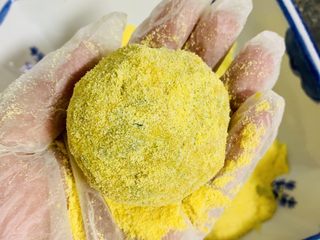 7、玉米面菜团子,一边给小菜球上放干玉米面粉，一边用双手轻轻对捏，让干玉米面粉全部粘在菜球上，这个动作反复做，直至做到你喜欢的厚度。（因为反复地挤压菜球，这个时候菜球内部的水分会吸住表面的干玉米面粉，最后双手，在轻轻对捏几次表面没有干粉即可。）