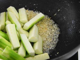 4、绿色清新的家常小菜—蒜蓉炒丝瓜,放入丝瓜，加盐中大火翻炒至变软。