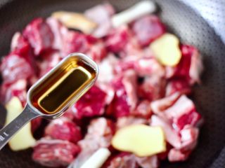 5、牛腩炖萝卜,再倒入料酒去腥增香。