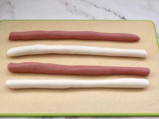 3、黑糖蜜桔酒酿圆子,把两个颜色面团揉匀,分别搓成细长条后,一刀切两段,分成4段,把颜色错开。