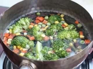 3、鲜虾玉米饼,小锅中添适量清水烧开，先将西兰花放入锅中焯烫两、三分钟，再把冷冻蔬菜也放进去烫两分钟，捞出沥干水分。