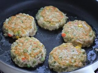 8、鲜虾玉米饼,开小火煎至一面定型变色后翻到另外一面继续煎制，直到两面都变成焦黄色即可。