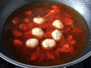 6、金针菇墨鱼丸子汤,大火继续快速翻炒至番茄变软后,锅中倒入适量的清水,加入墨鱼丸子。