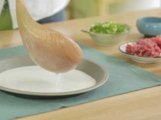 8、宝宝版牛肉肠粉,舀一小勺粉浆倒入平盘里，均匀铺开，越薄越好，越薄做出来口感越好。记住，每舀一勺前，要将粉浆搅拌一下，因为粉浆放久了会发生沉淀分层。