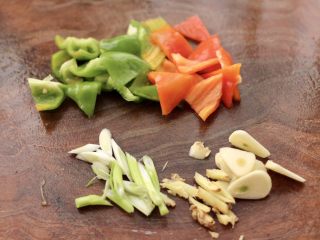 2、啤酒焖鳕鱼,青椒和红椒用刀切成片，葱姜切丝。