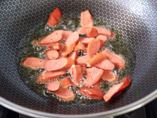 4、小白菜火腿小炒,锅烧热后，倒入花生油烧至六成热时，放入火腿片，小火慢慢煎至。