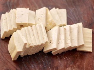 2、照烧北豆腐,把豆腐用刀切成薄片。