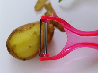 2、家常辣炒土豆丝,土豆洗净后,用削皮刀去除土豆外皮。