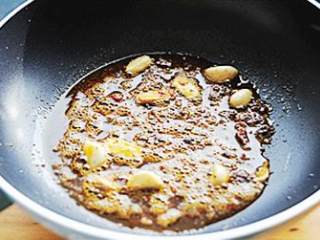 3、干锅千页豆腐,不粘锅加油烧热(其它锅热锅凉油),加入麻辣火锅料、姜片和蒜瓣小火炒香。