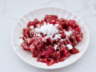 2、牛肉粒香辣藕丁,把牛肉粒放到盘子里,放入淀粉和料酒,适量的盐调味。