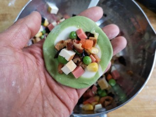 17、八宝百财蒸饺,在饺子皮中间填入适量的馅（饺子皮面积的一半为宜）。填馅料时注意皮的收口处一定要干净，不然容易捏不紧。