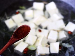 11、海带豆腐炖梭子蟹,再倒入料酒调味。