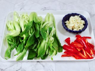2、蒜蓉小油菜,把小油菜用刀一切两半,红椒去籽后切条,大蒜去皮切碎。
