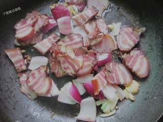 7、腊肉土豆片,倒入腊肉翻炒，小火慢慢煎煮，直至腊肉肥肉微微发焦，油脂煎出来