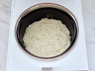 4、绿豆红薯饭,把浸泡后洗净的大米，放入臻米脱糖养生蒸汽饭煲的甑锅里。