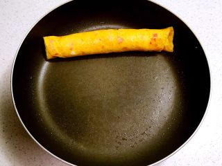 12、双色厚蛋烧,蛋黄液上面基本凝固的时候卷起来，尽量卷得紧实点，卷好后把蛋黄卷放到锅的一侧