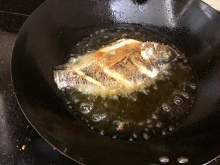 7、酸甜开胃的糖醋鱼,油烧到七成热,把鱼顺锅边滑入油锅。