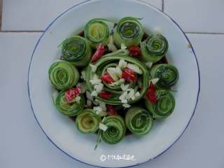 5、响油黄瓜卷,把汁淋在黄瓜卷上，放上蒜末、辣椒