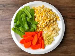 3、虾仁炒杂蔬,荷兰豆掐掉头尾洗净，胡萝卜刮掉外皮切成薄片，把玉米粒一个个剥下来，蒜去皮切片，姜去皮切末。