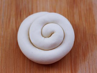 11、卤肉夹馍,然后把长条从一头开始卷起，卷到最后把尾端压在面团底下。