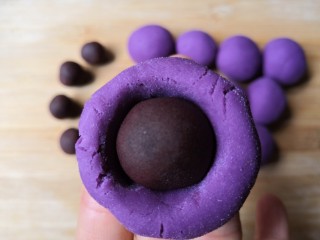 9、西米紫薯球,拿一个紫薯球，把中间压一个窝，放入豆沙馅，收口撮圆。