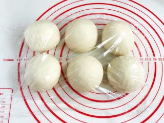 6、贝果汉堡包,将发酵好的面团取出排气，平均分成6份，接着滚圆，盖好保鲜膜松弛15分钟。