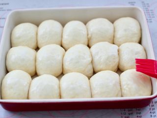 10、牛奶杏仁小餐包,表面喷上一些水保持湿润，盖上保鲜膜放入烤箱进行二发，发至原来的2.5倍大，约模具的8分满取出刷上蛋液。