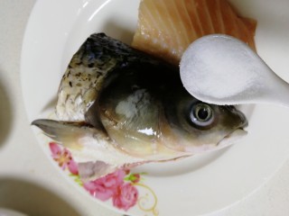 3、鱼头豆腐汤,洒半小勺盐，鱼头表面搓匀，腌制5分钟。