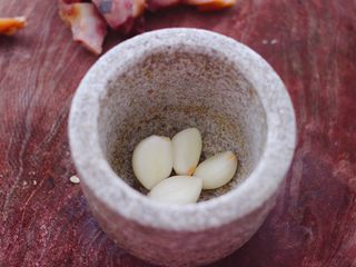 5、猪头肉拌黄瓜,把大蒜去皮后,把蒜瓣捣成蒜泥。