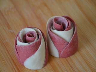 21、玫瑰花馒头,将切开的两个花卷立起来，这样就是两朵漂亮的玫瑰花，每个玫瑰花馒头生胚约46g左右。这是粉色花瓣在外面的玫瑰花馒头。