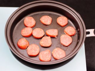 5、对虾红肠时蔬泡面,用煎蛋的锅，直接把切片的红肠放入煎锅中。