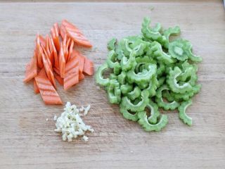 2、苦瓜炒虾仁,苦瓜洗净从中间剖开，挖去瓜瓤切成片小片，胡萝卜去皮切菱形片，大蒜切碎备用。