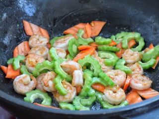 6、苦瓜炒虾仁,再将苦瓜和胡萝卜放入锅中，改大火快速翻炒三十秒。