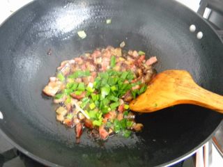 5、腊肉糯米卷,炒勺放一勺油，不要多，一汤勺足够，放入葱白部分炒香,在放入腊肉肉丁翻炒,炒到腊肉肥肉部分微微透明,放入葱叶