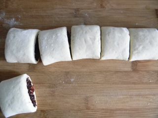 8、腊肉糯米卷,把做好的生胚移到一个木质案板上，手起刀落，高抬刀快速把面卷切小段，这样面卷的的切口才整齐不塌陷