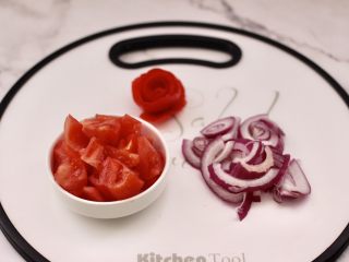 5、香煎三文鱼&炒意面,洋葱用刀切丝,把番茄用刀去皮后切小块,番茄皮直接卷个小花朵留着摆盘用。