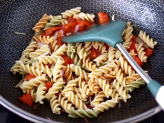 11、香煎三文鱼&炒意面,把煮熟的彩色意面倒入锅中,大火翻炒均匀。