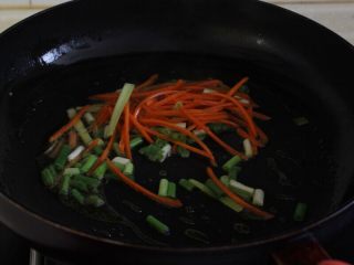 6、油条韭黄炒墨鱼,8.热锅热油先下入葱姜蒜和胡萝卜丝炒出香味。